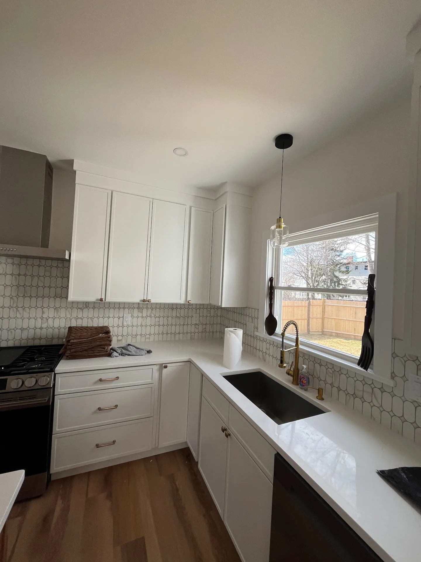 Completed Medford kitchen with white painted shaker-style cabinets and warm metal pulls