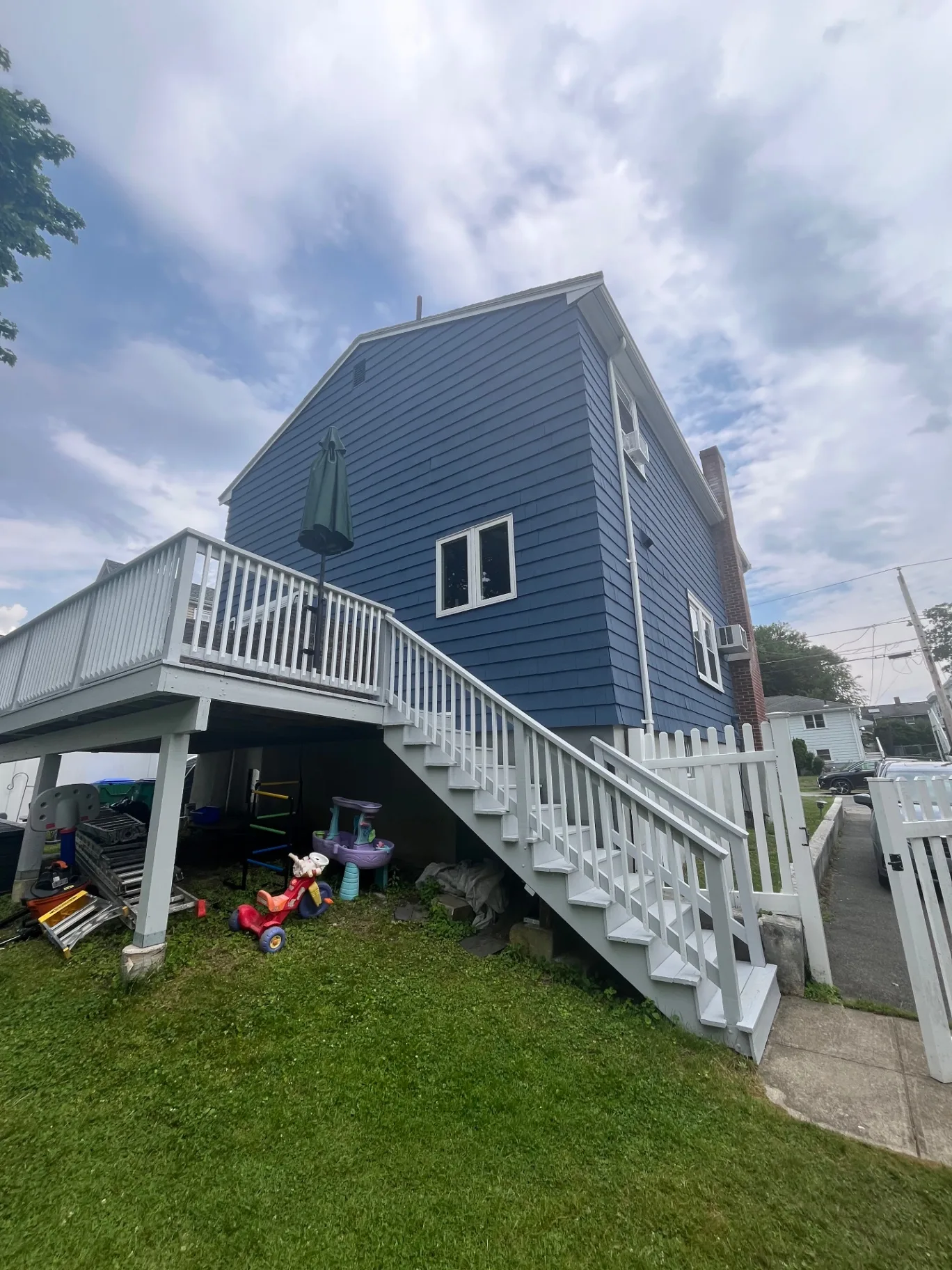 Medford home exterior with navy painted shingles, white trim, deck rails and stairs
