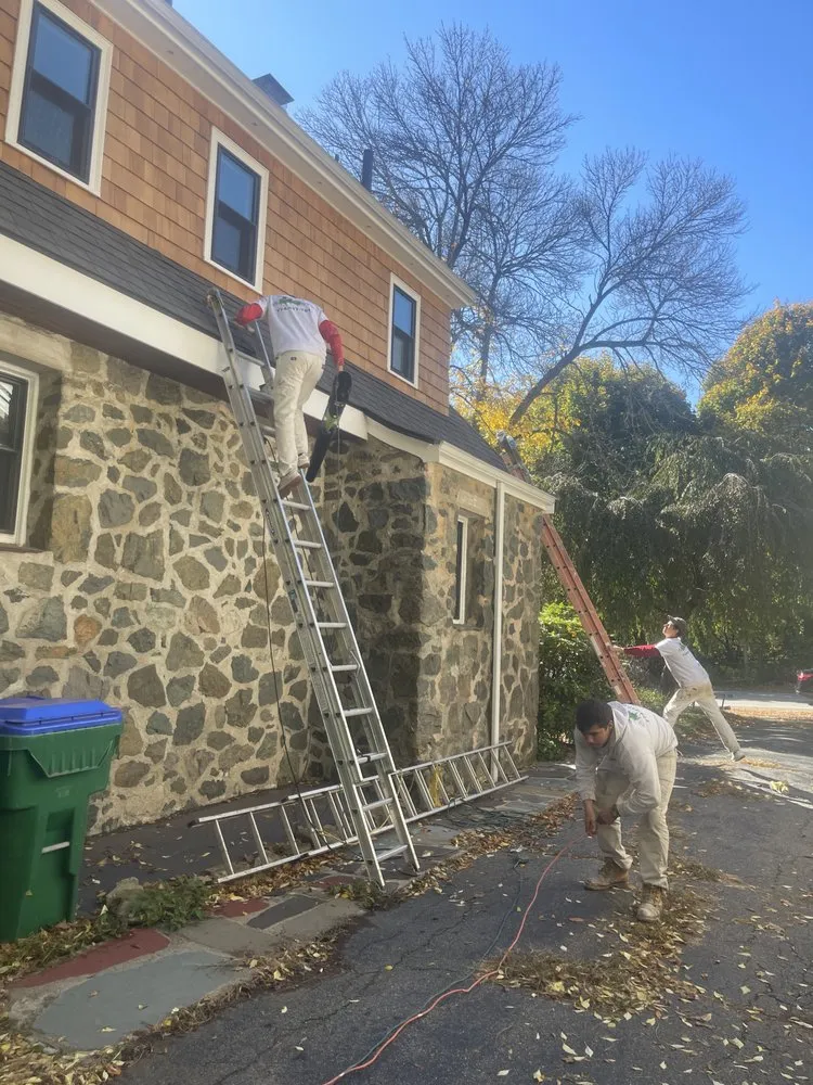 Professional exterior painting team with ladders on two-story home in Revere MA
