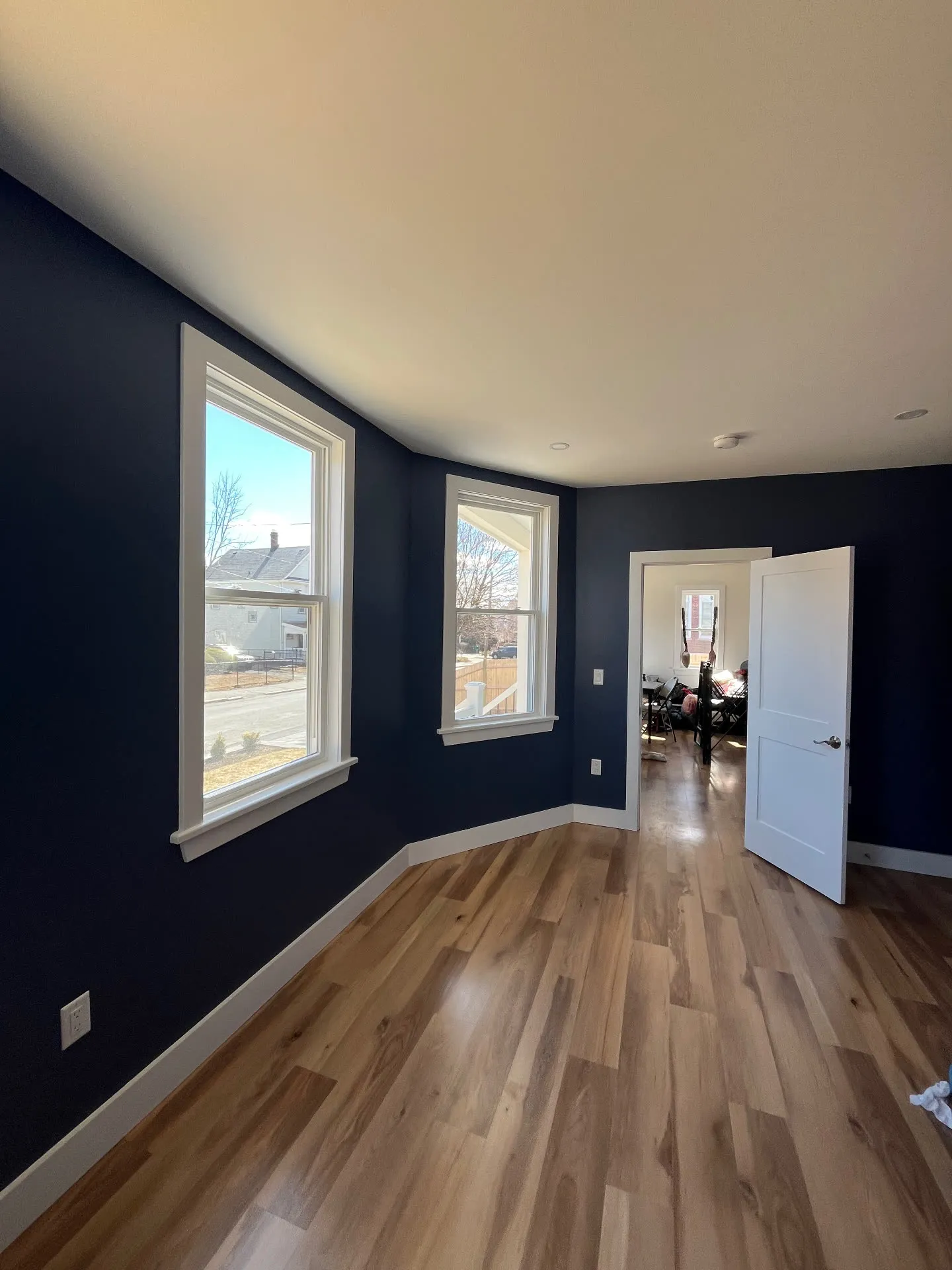 Finished Medford bedroom with deep navy painted walls, white trim and natural wood flooring
